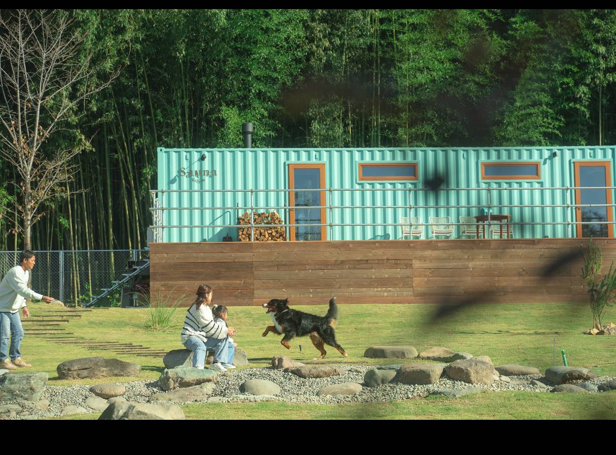 コンテナサウナと庭で遊ぶ家族と犬